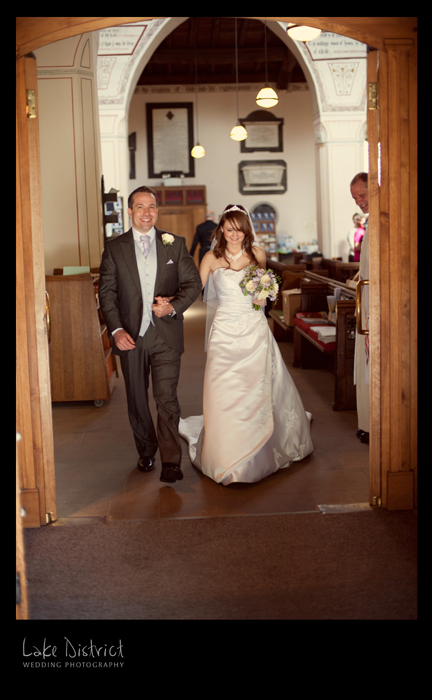 photograph of bride and groom coming out of a church in the lakes